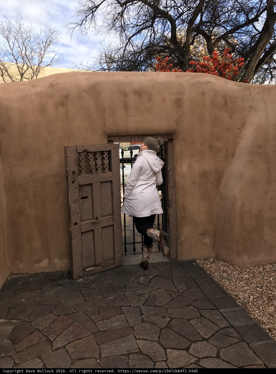 A Woman Stands Before An Adobe Door