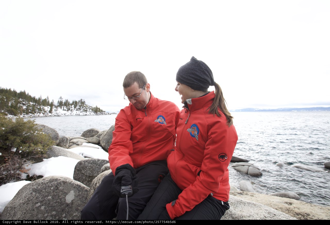 Couple in Red Jackets at Snowy Lake Tahoe Shore