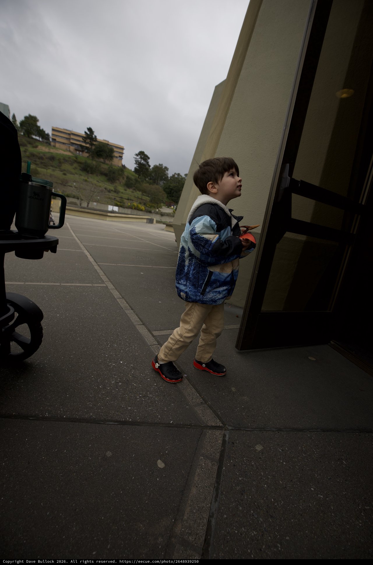 Young Boy Looking Up at Bus on Overcast Day