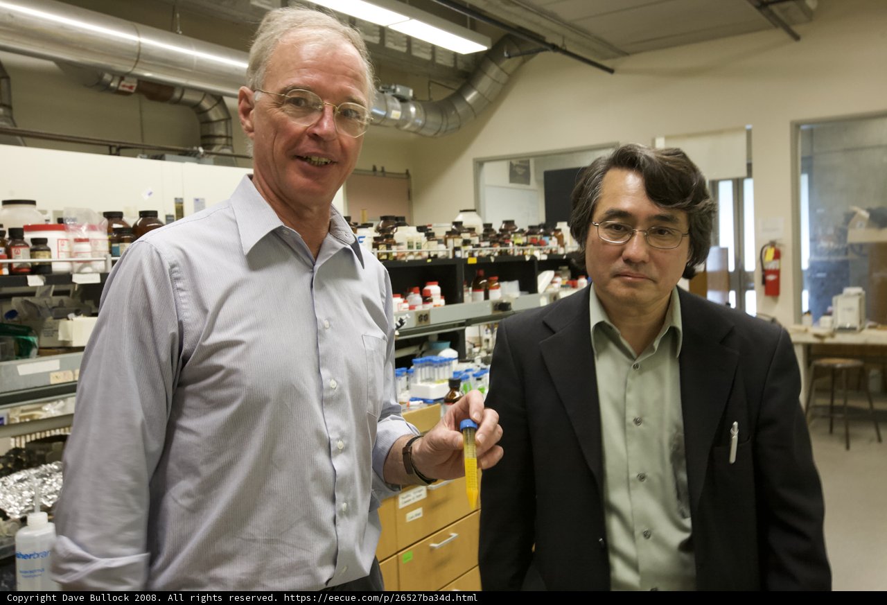 Two Men in Lab Coats Work at a Bench