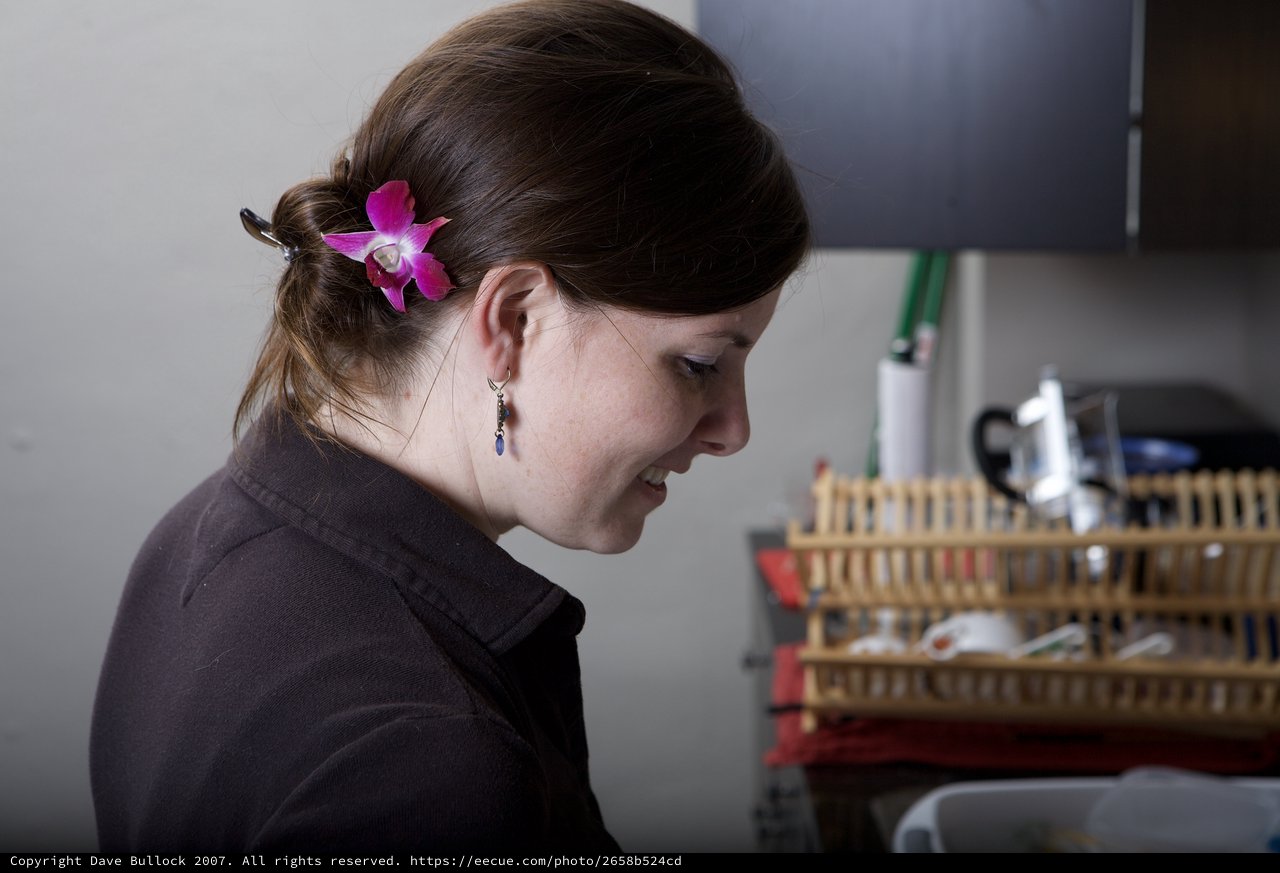 Woman with Pink Orchid in Hair at Kitchen Sink