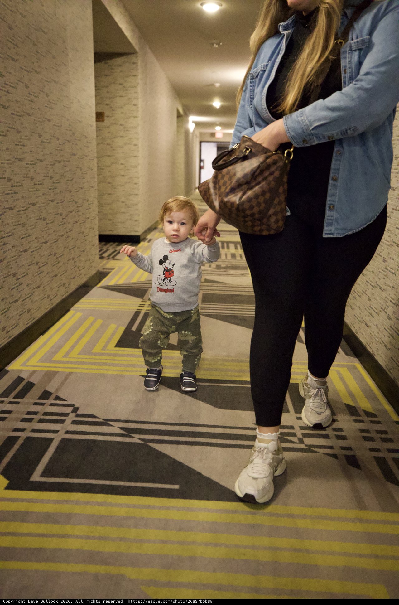 Toddler and Mother Walking Through Hotel Corridor