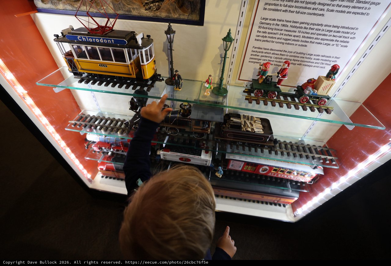Child Exploring Vintage Train Models at Museum Display