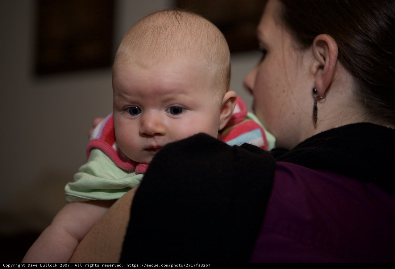Baby's Wide-Eyed Gaze Over Mother's Shoulder