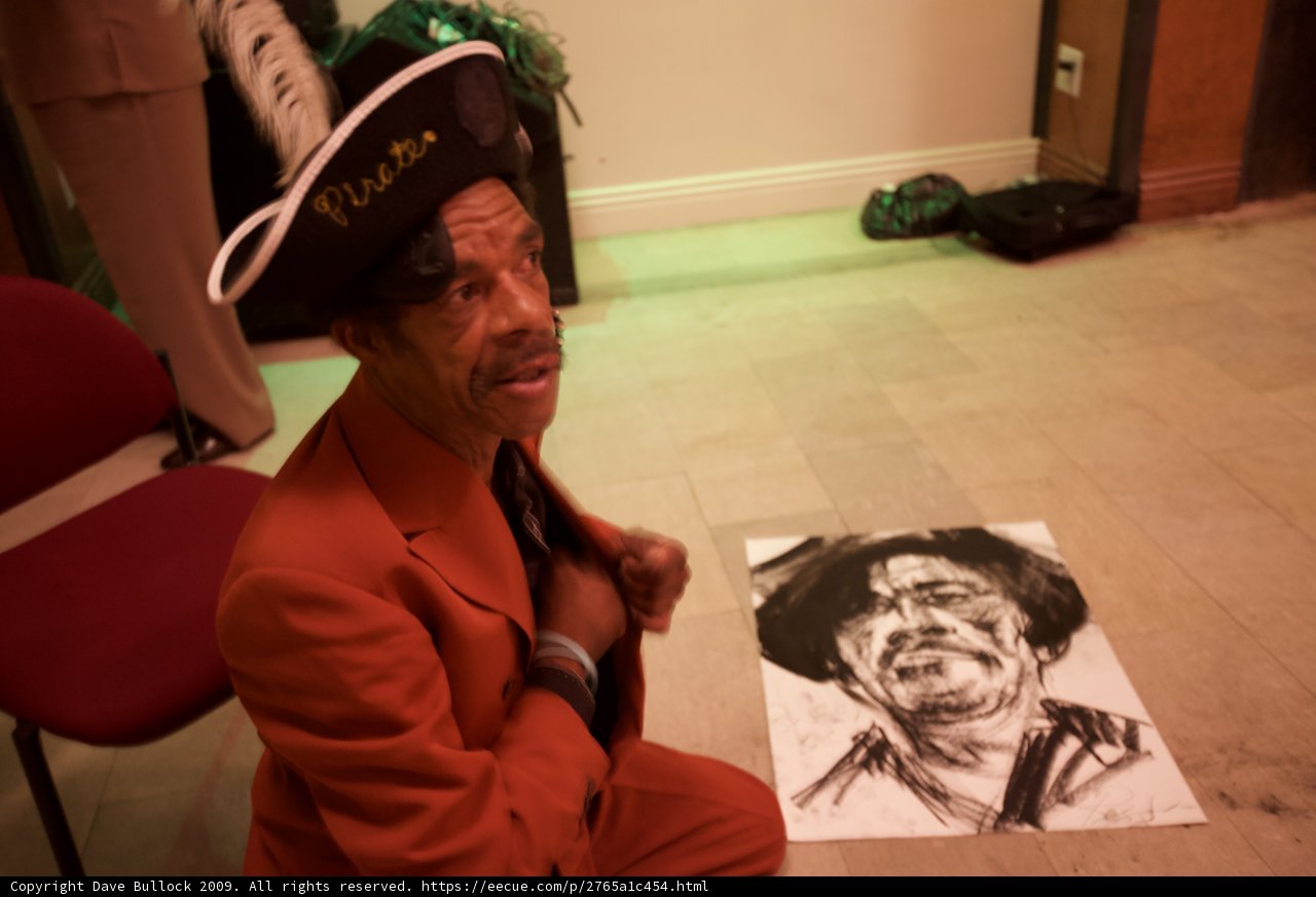 Man in Suit and Hat with Artwork on Hardwood Floor