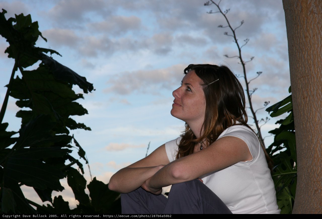 Woman Gazing Upward at Dusk Amid Tropical Foliage