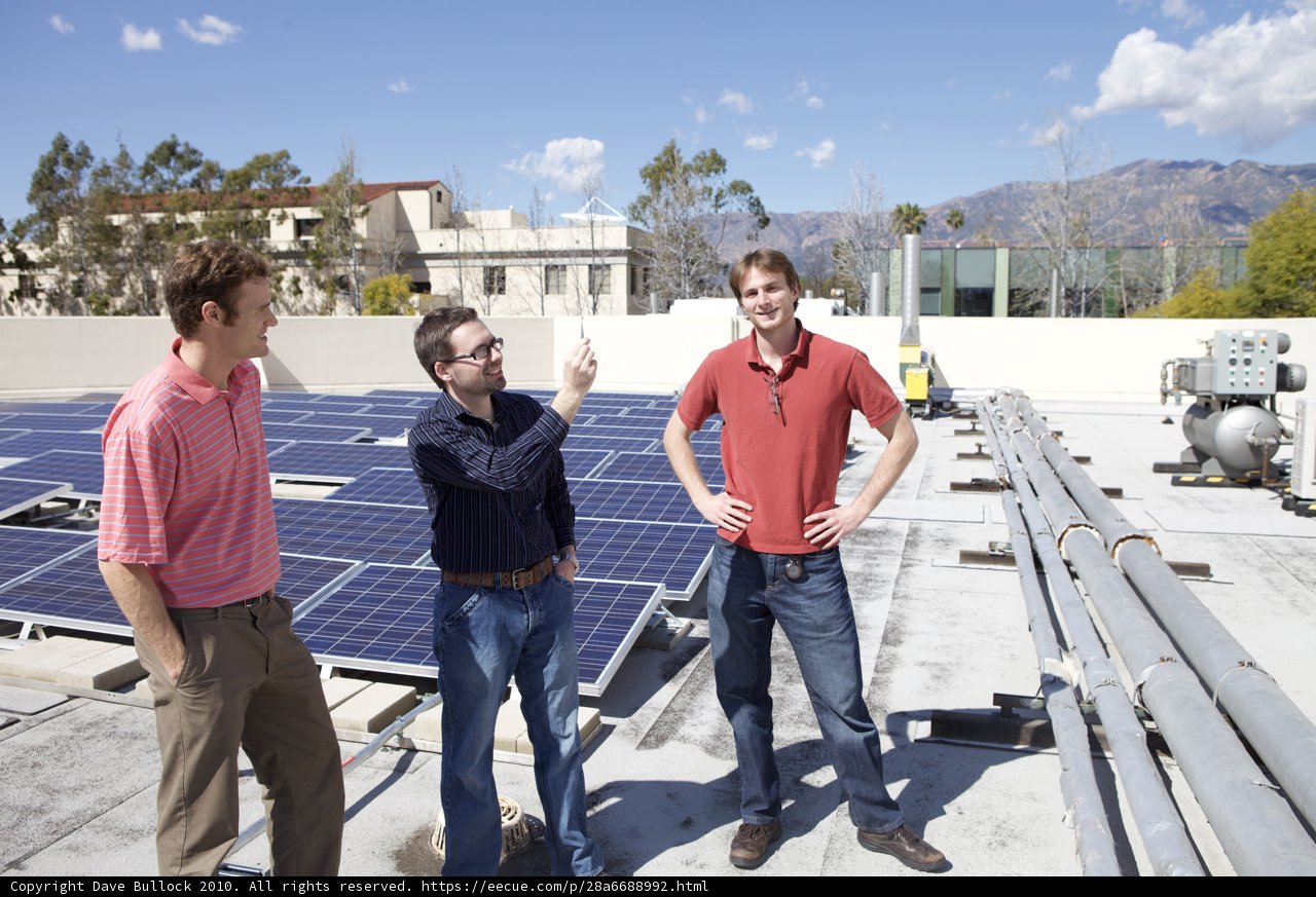 Three Men Working on Solar Panels on Rooftop