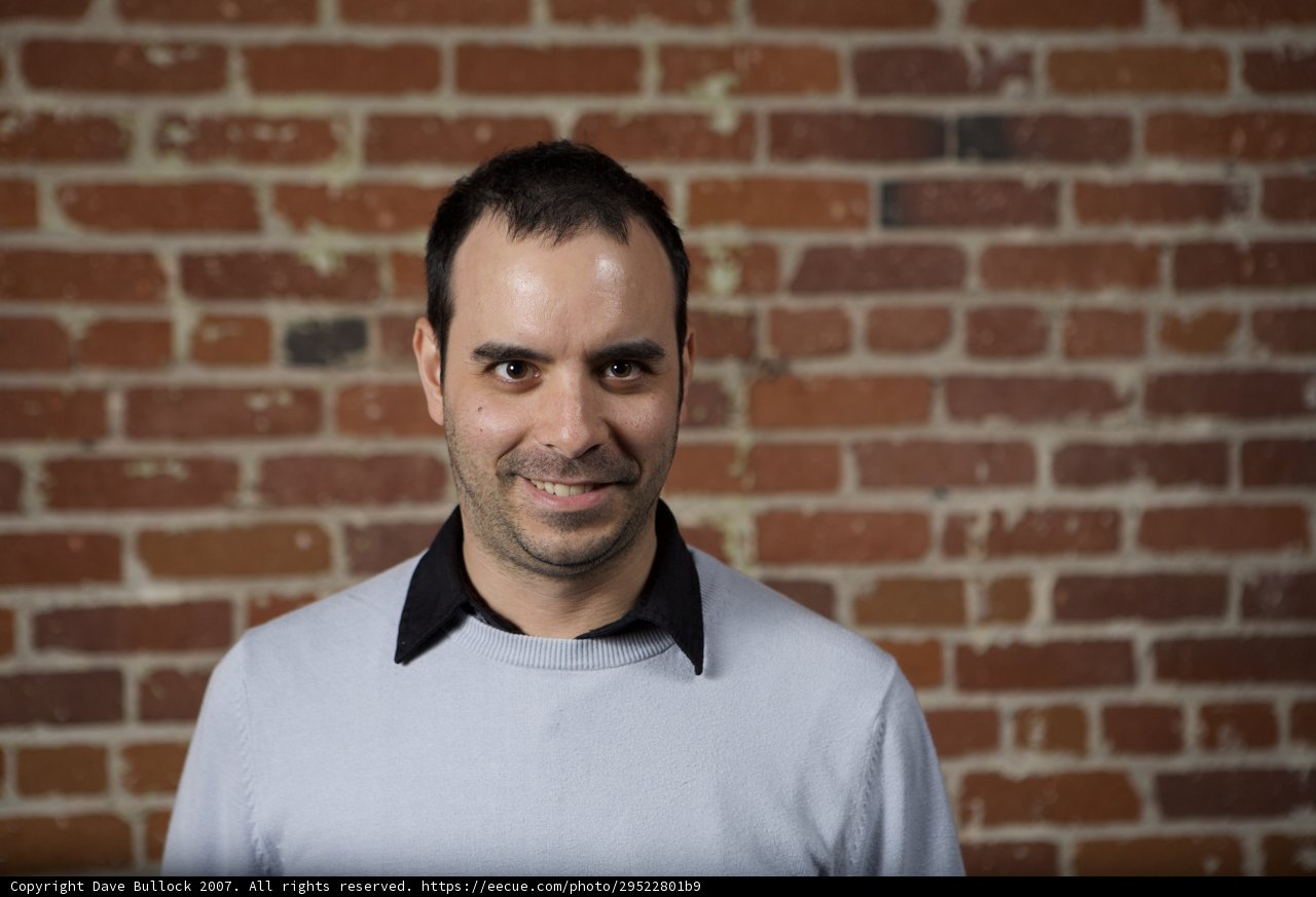 Grey sweater guy posing in front of brick wall