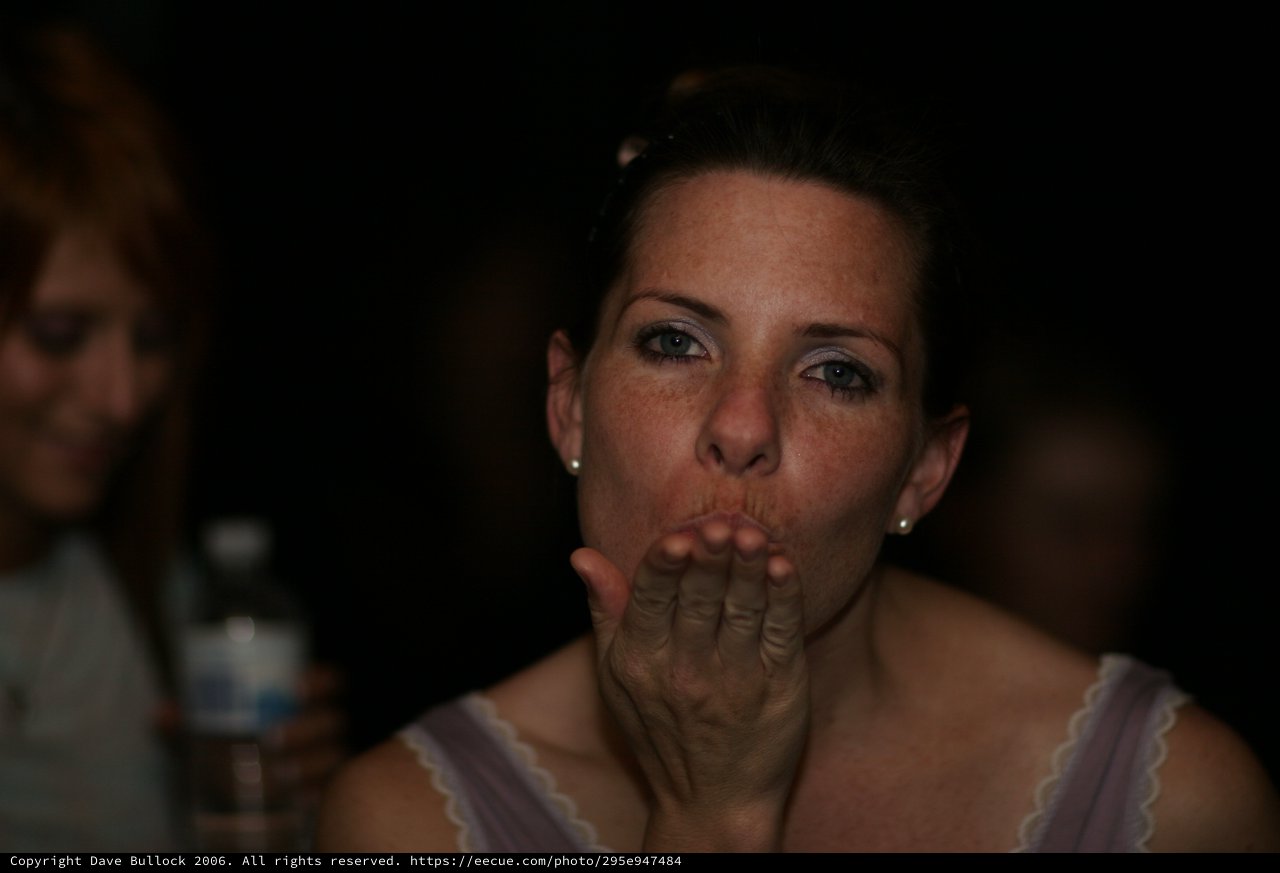 Woman Blowing a Kiss in Dim Party Light