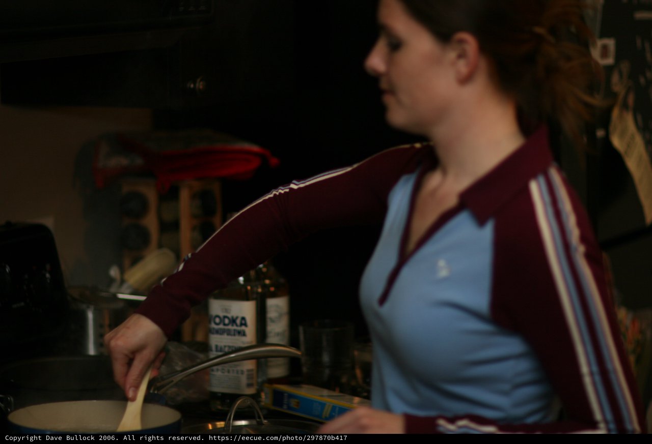 Woman Cooking with Vodka in Dim Kitchen