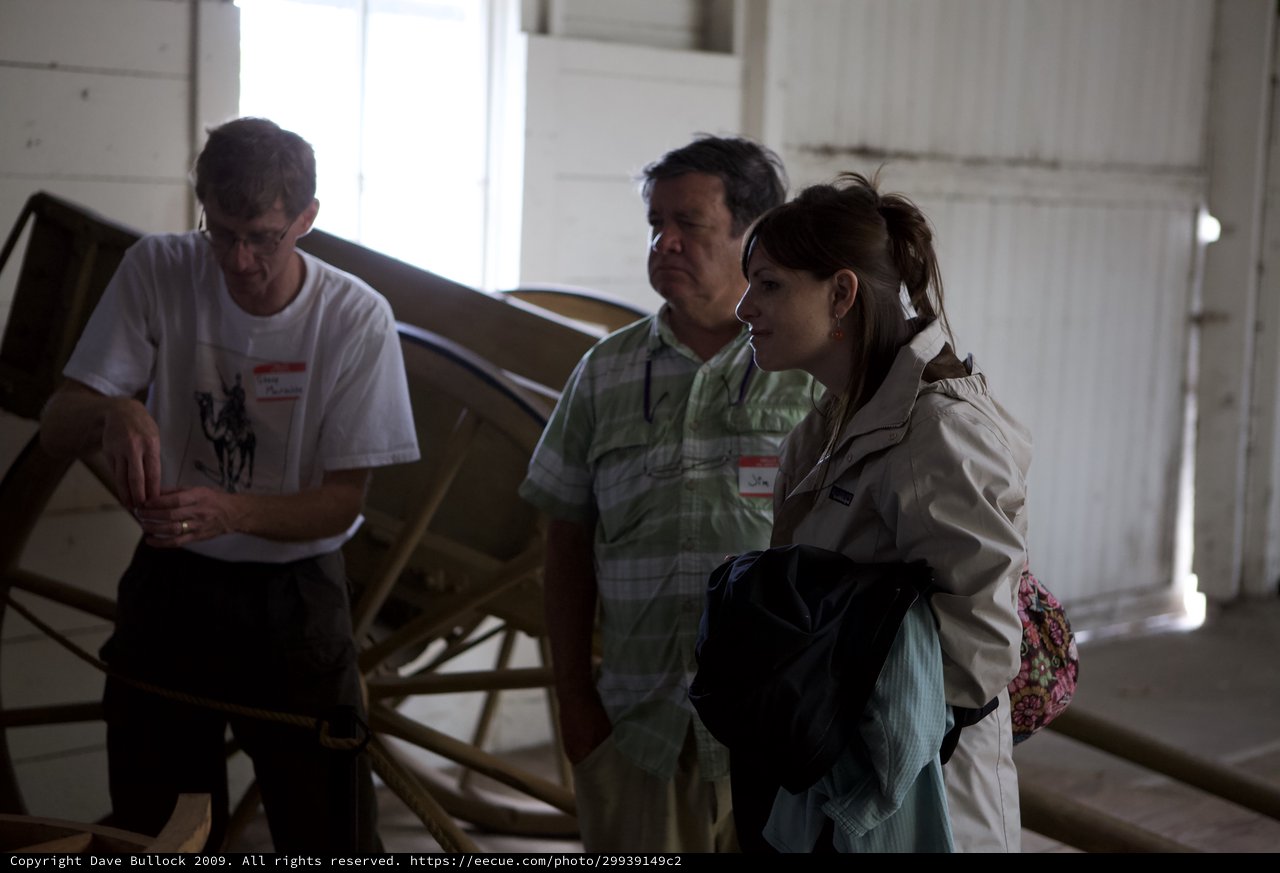 Visitors Examining Historic Wooden Wagon at Museum