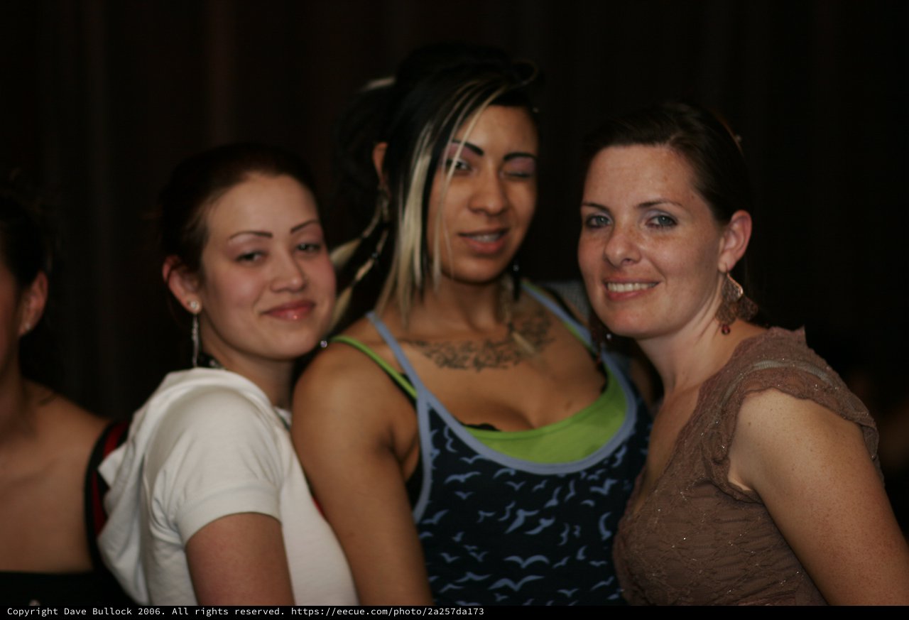 Three Women Smiling Together at Nightclub Event