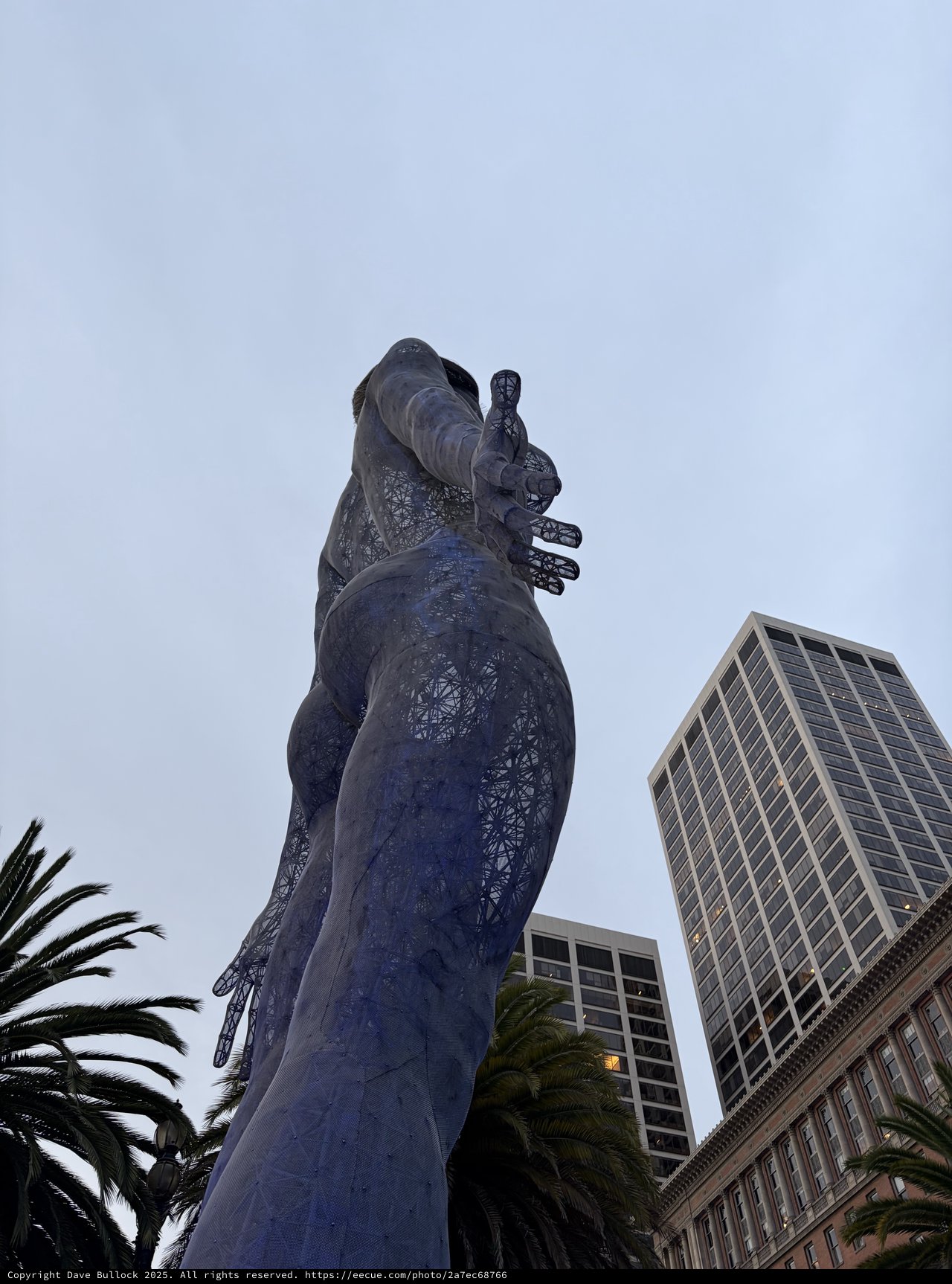 Towering Goddess Statue Against Urban Skyline