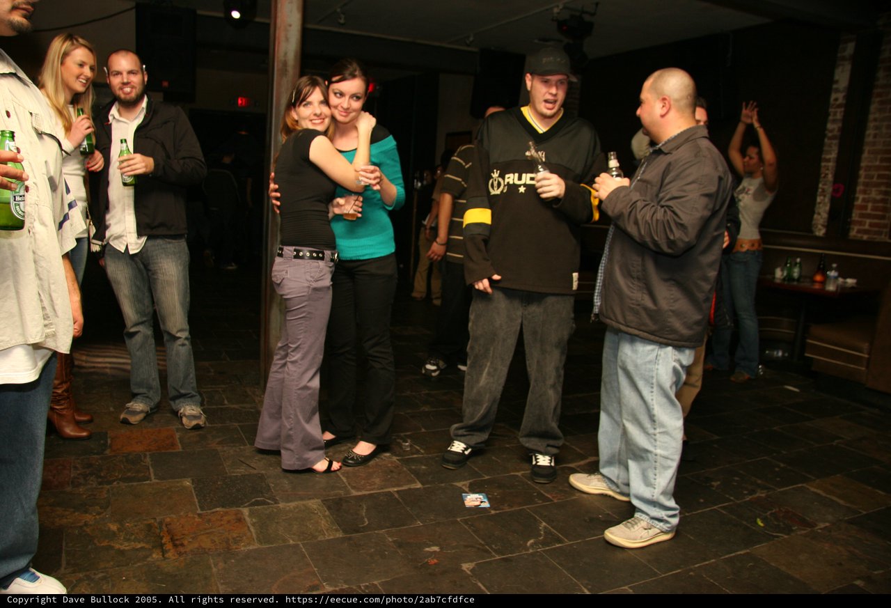 Friends Embrace at a Lively Holiday Bar Gathering