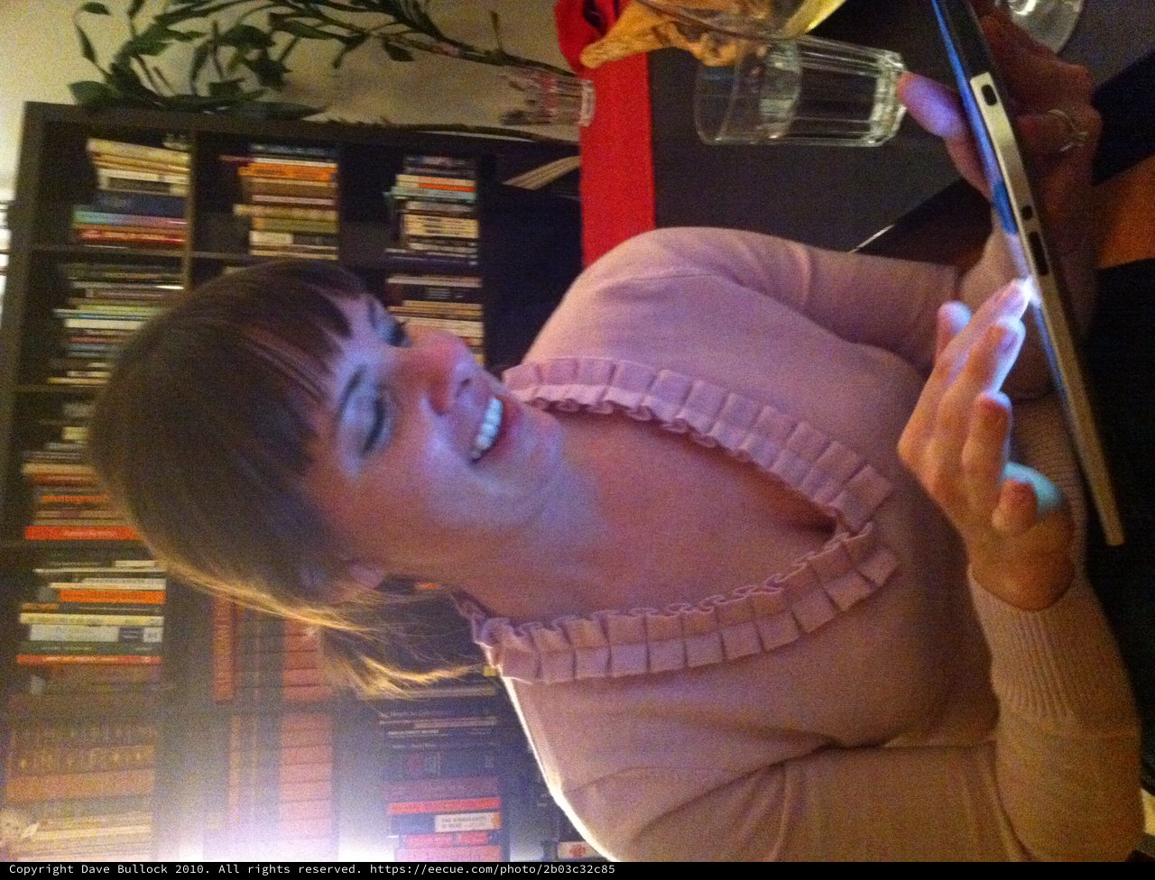 Woman Smiling While Using iPad in Cozy Library