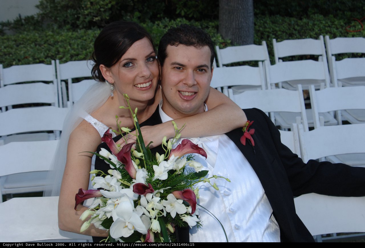 Newlyweds Embrace Amid White Wedding Chairs