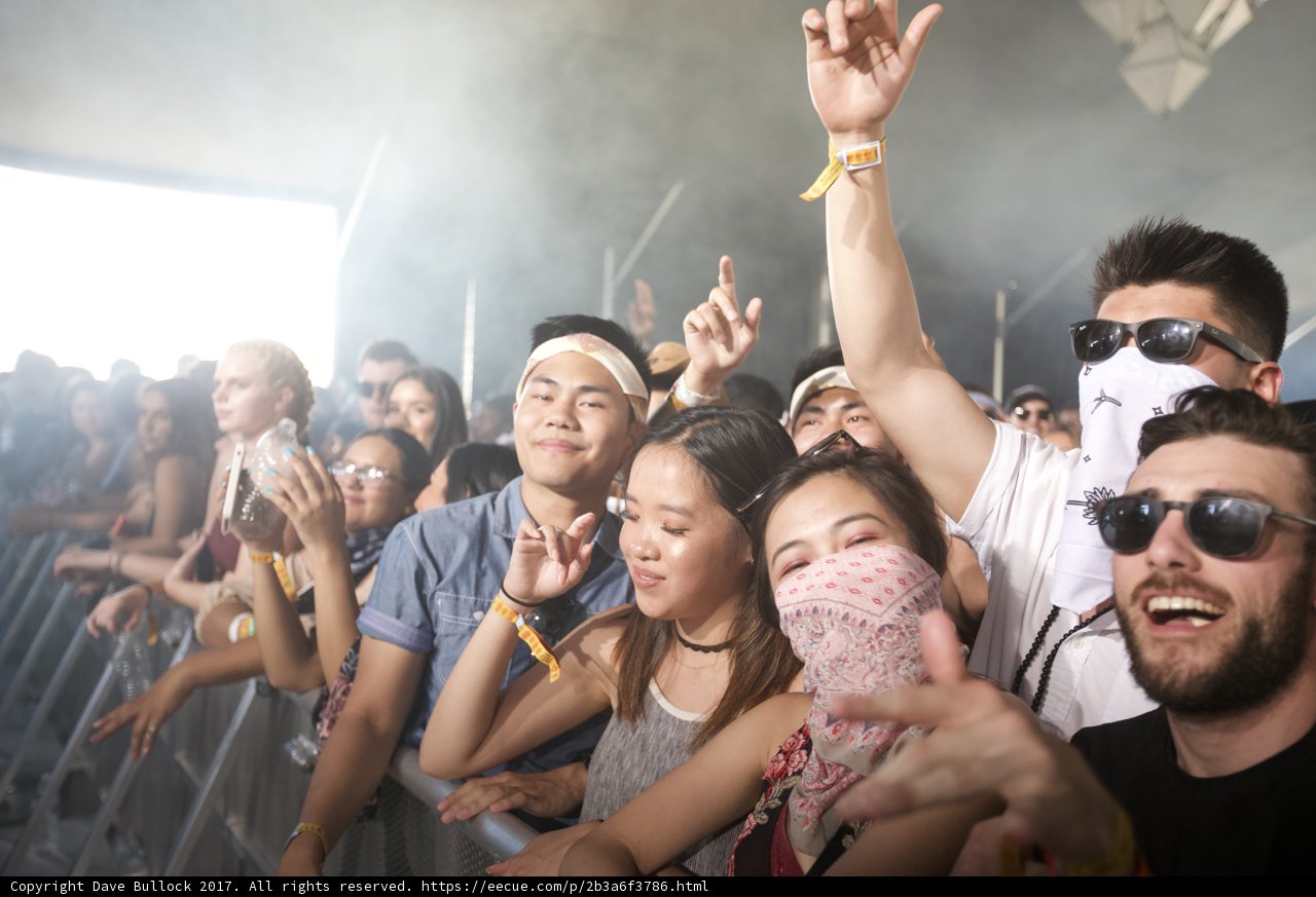 Lone Masked Figure in a Sea of Sunglasses
