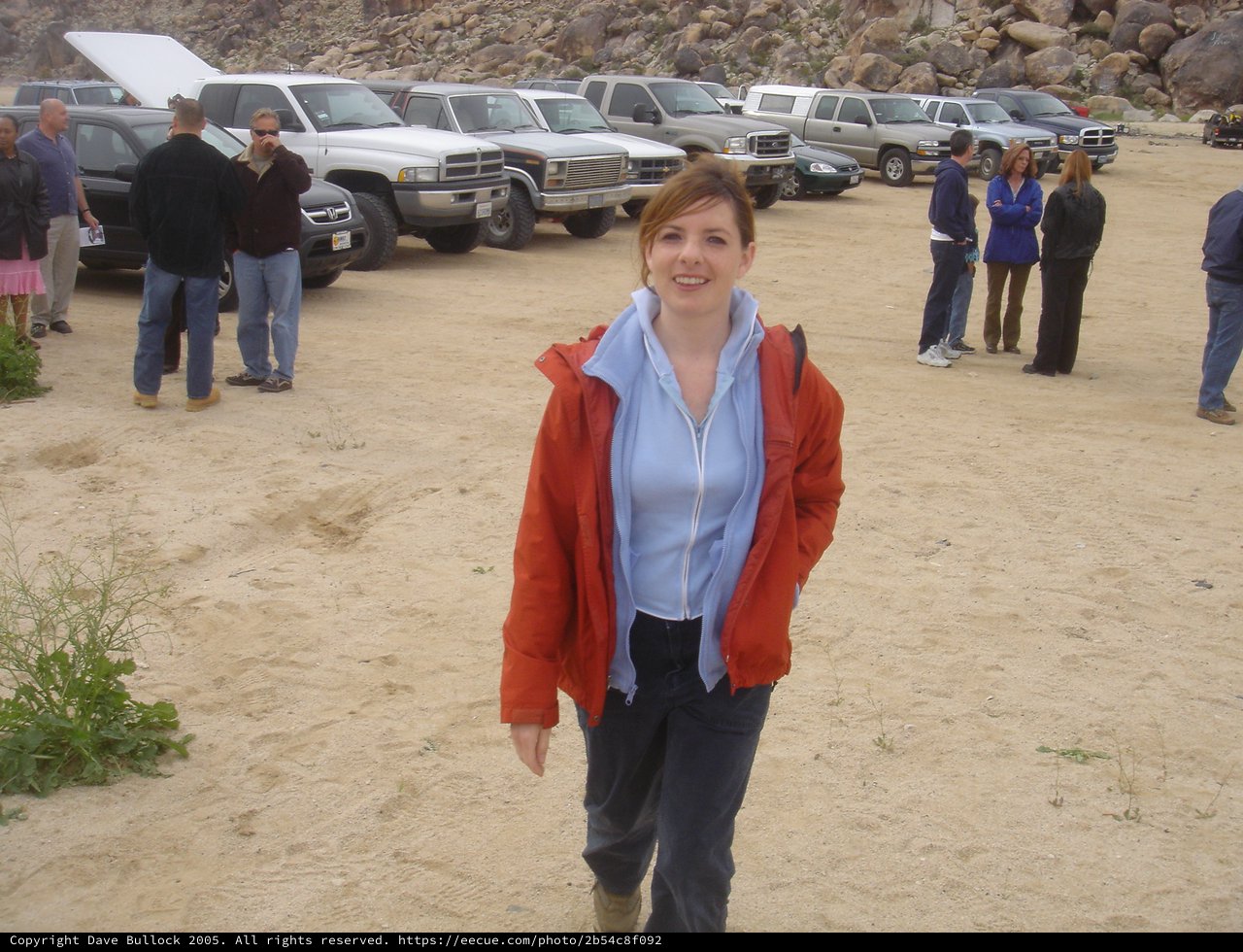 Woman Smiling in Desert Parking Area Near Rocky Hills