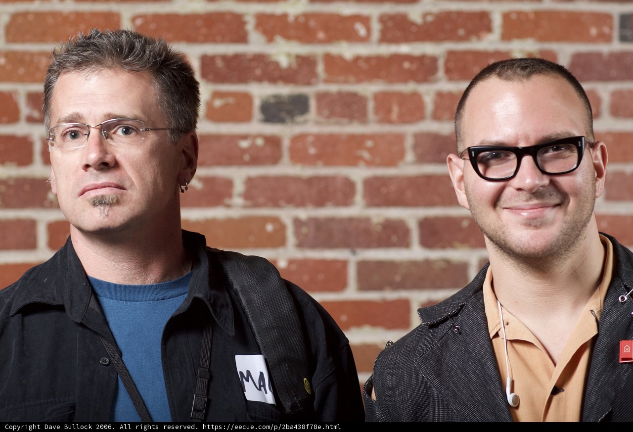 Two Men Smiling in Front of a Brick Wall