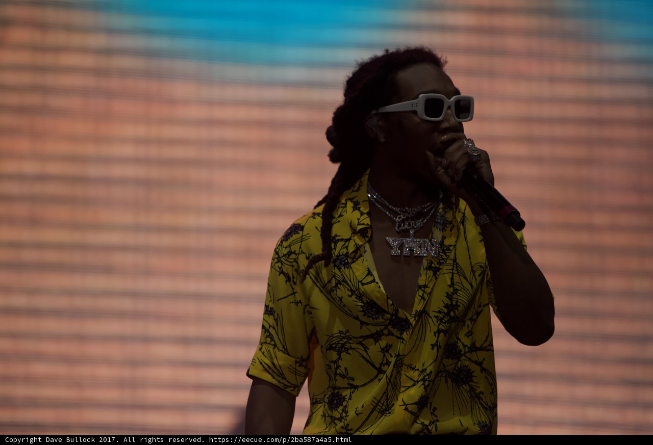 Live at Coachella Caption: A solo performer with dreadlocks and sunglasses rocks the stage, holding the microphone in one hand and energizing the excited crowd with the other.
