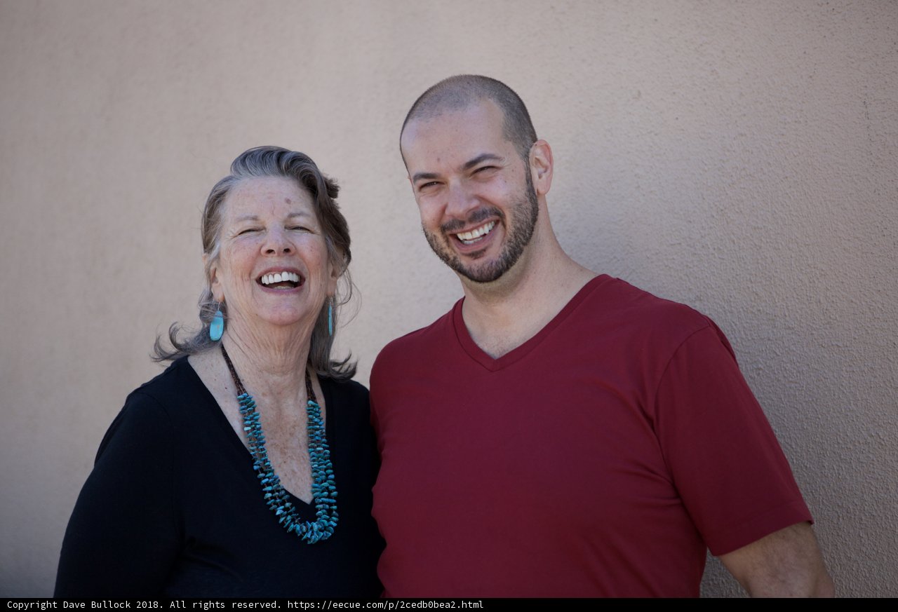 Smiling Portrait of Rhoda B and Dave B in Front of Wall