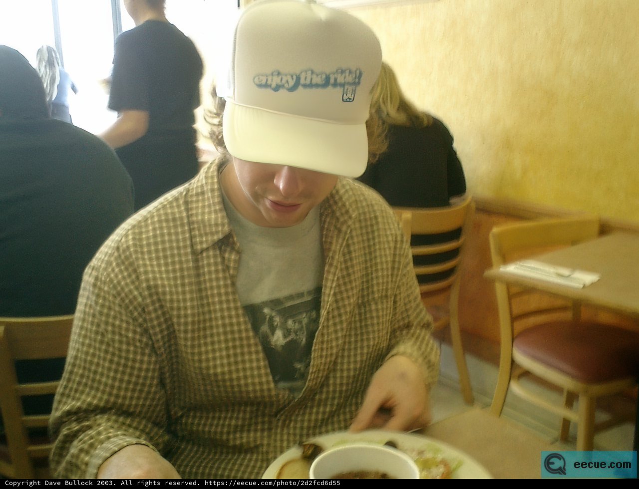 Man in a Baseball Cap Enjoying a Meal at a Downtown Cafe