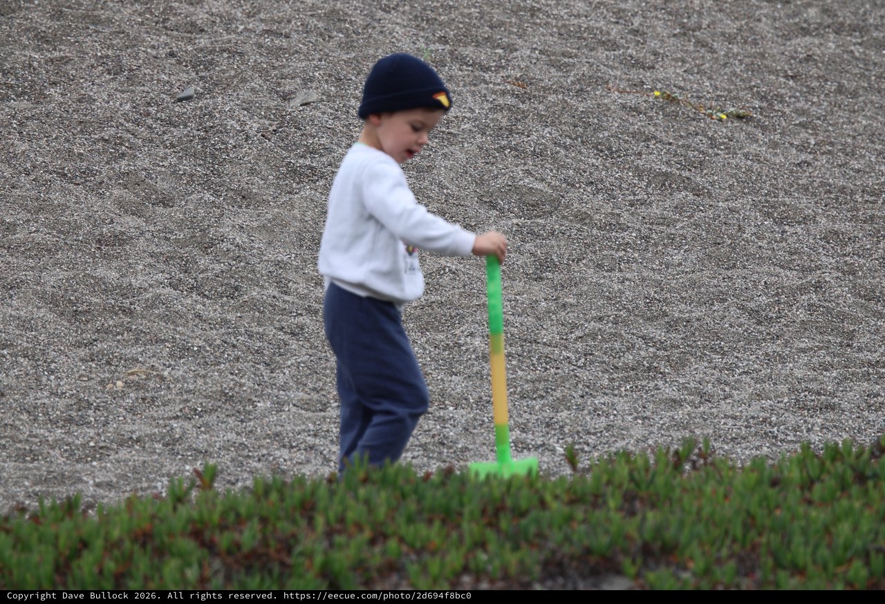 Young Boy Playing with Shovel on Sandy Beach