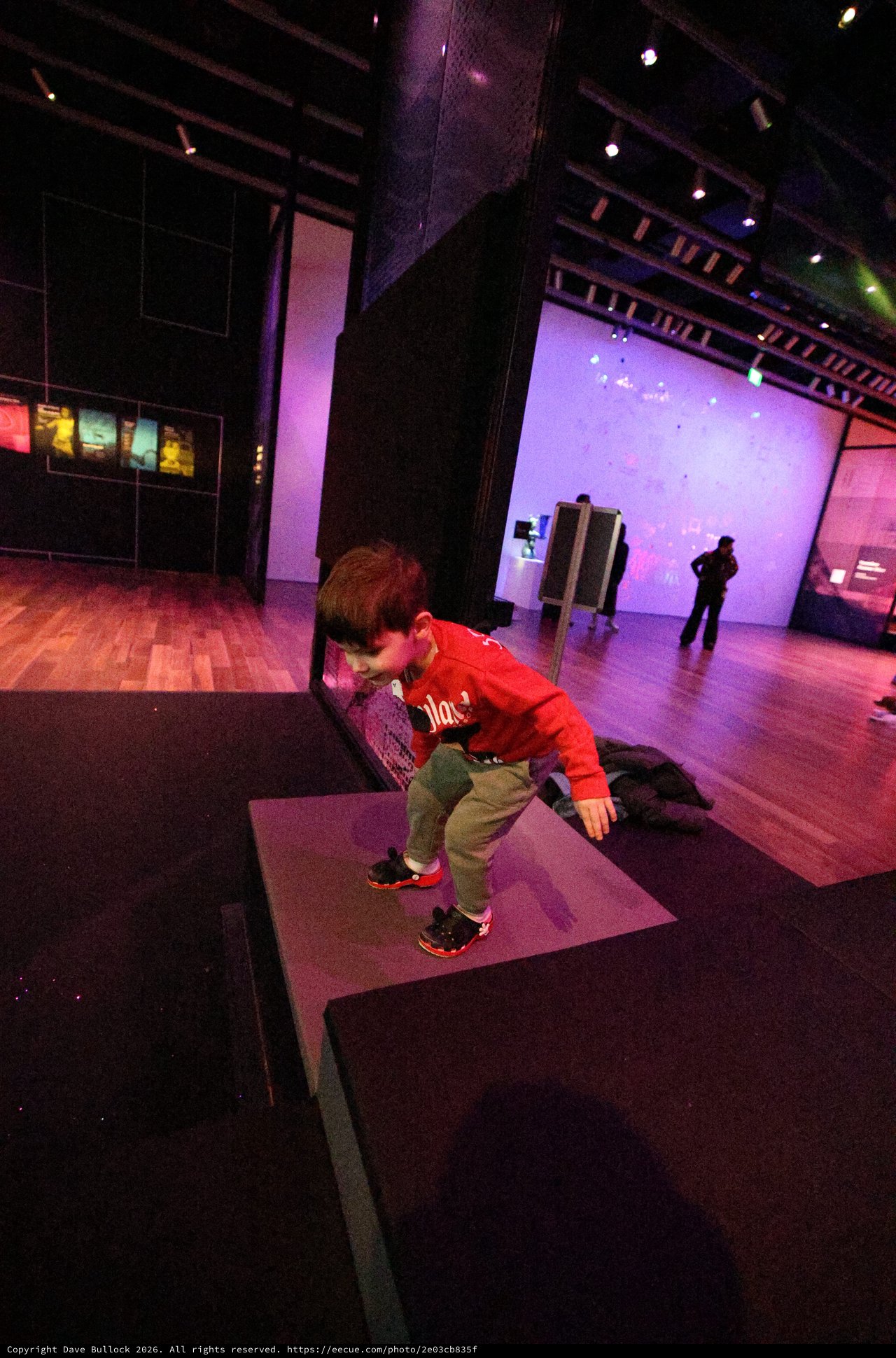 Child Exploring Interactive Museum Exhibit in Purple Light