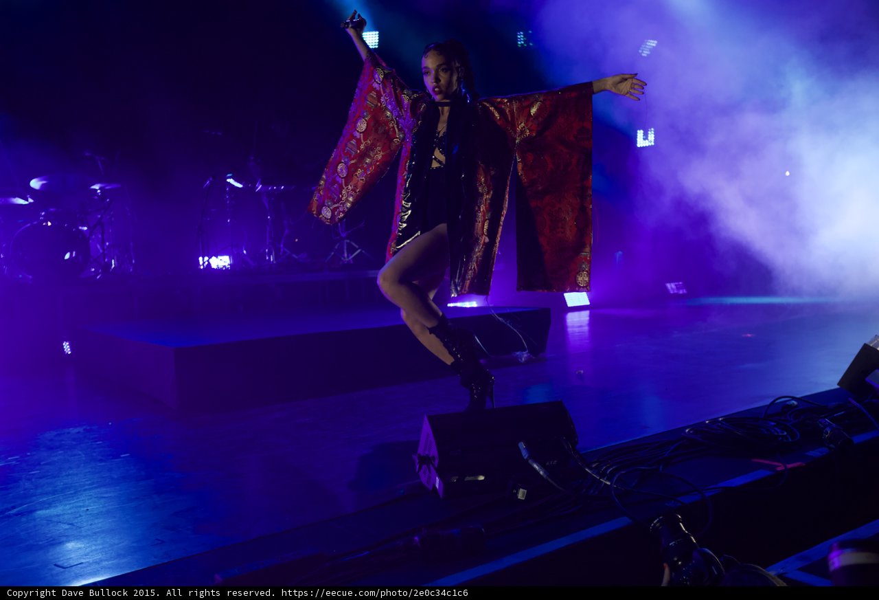FKA twigs Incredible Dynamic Dance Pose Leg Bent Arms Spread Kimono Wings Red Brocade Gold Patterns Black Strappy Bodysuit Boots Face Visible