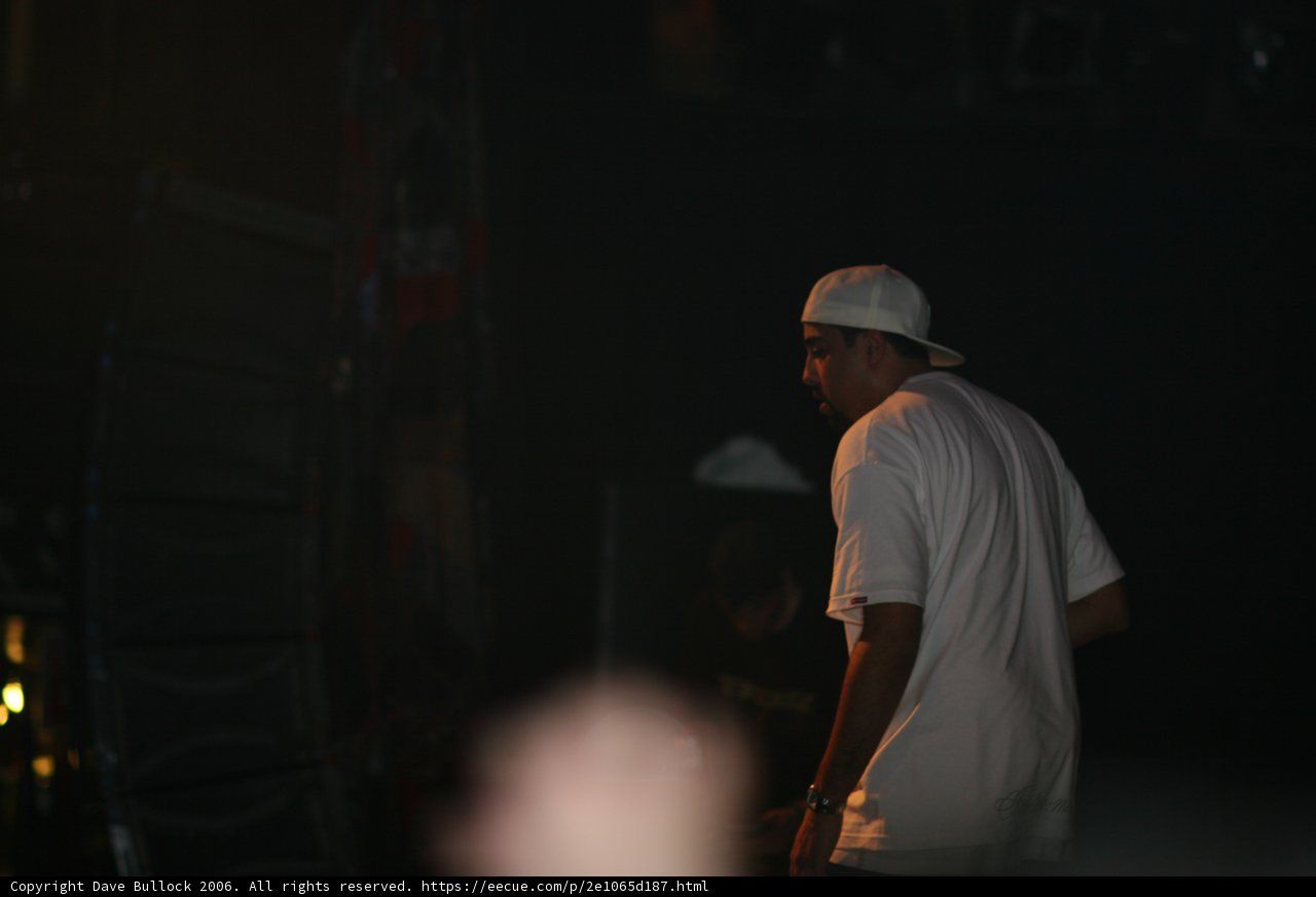 Man in White Shirt and Baseball Cap on Stage