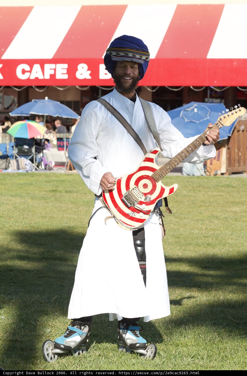 Man in White Robe Playing the Guitar Outdoors