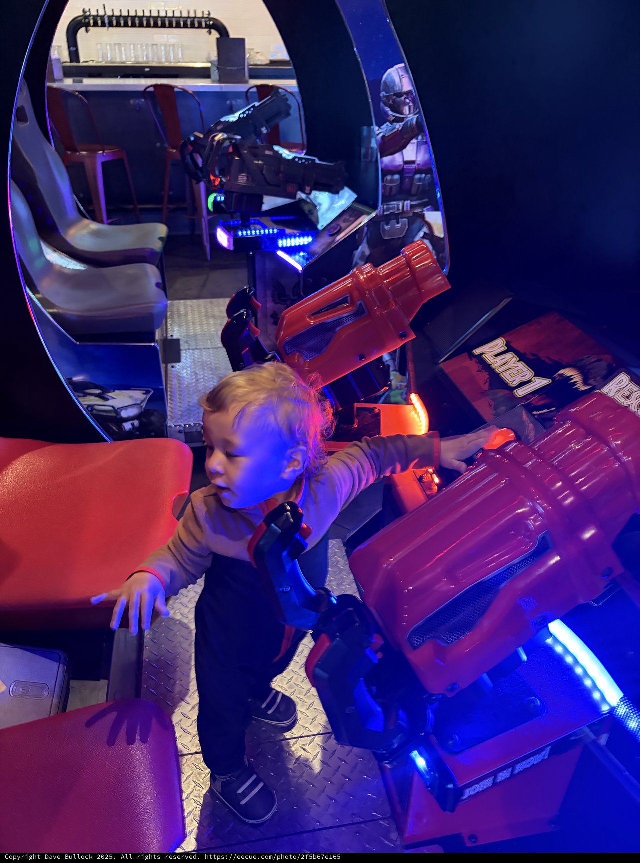 Child Playing Retro Arcade Games in Blue-Lit Gaming Pod