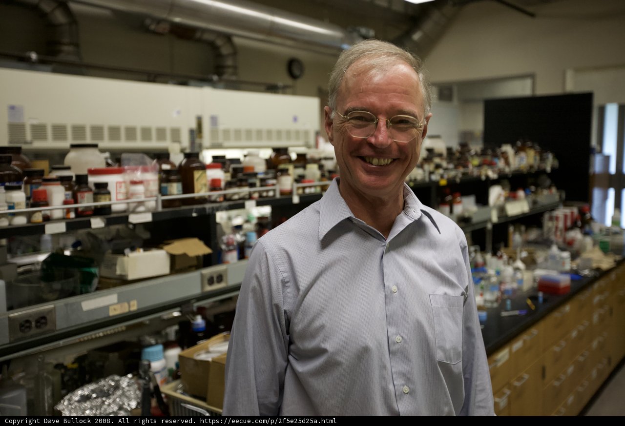 Lab Coat Man Posing in Front of Shelves