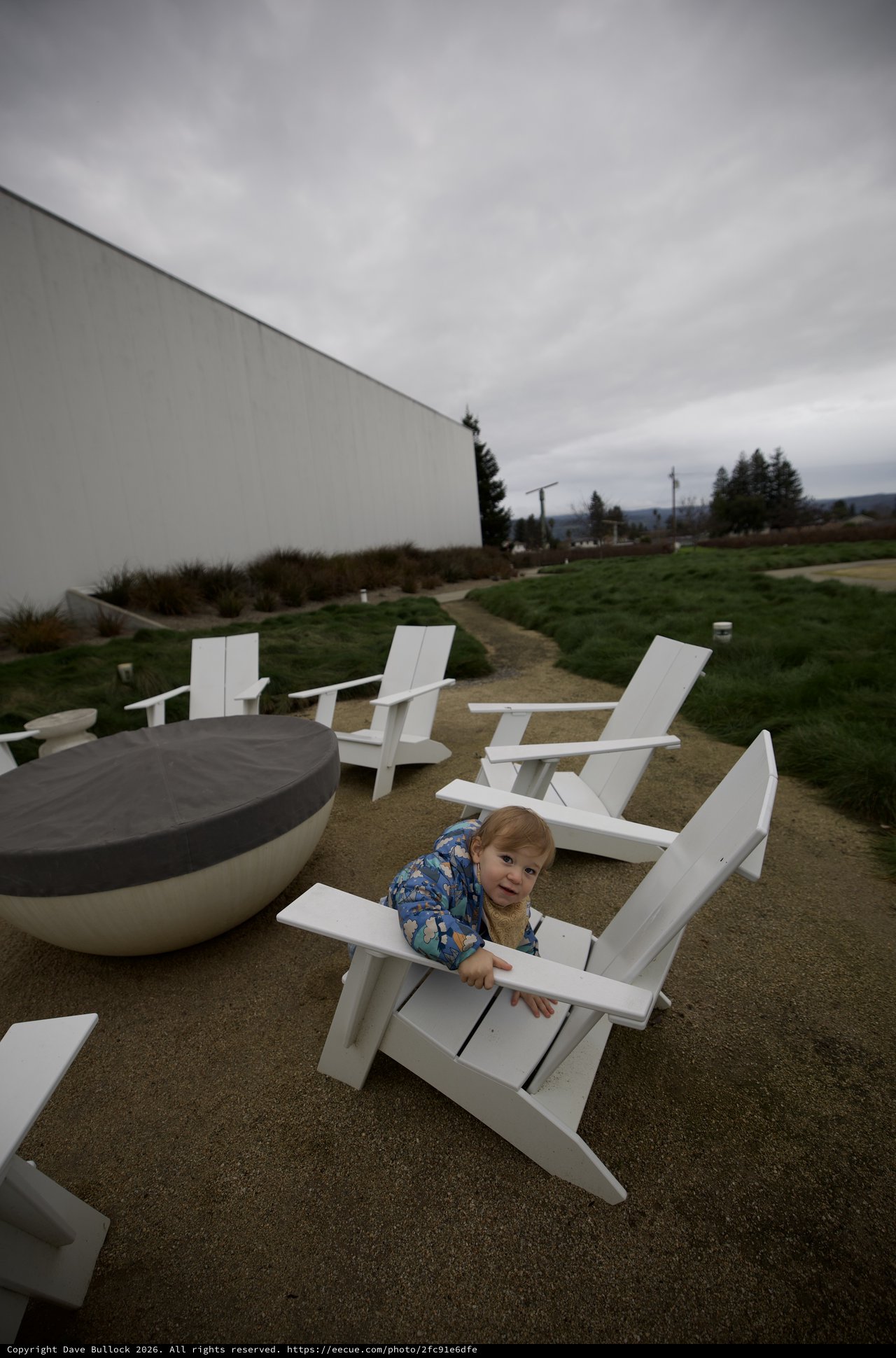 Toddler Playing Among Modern White Adirondack Chairs