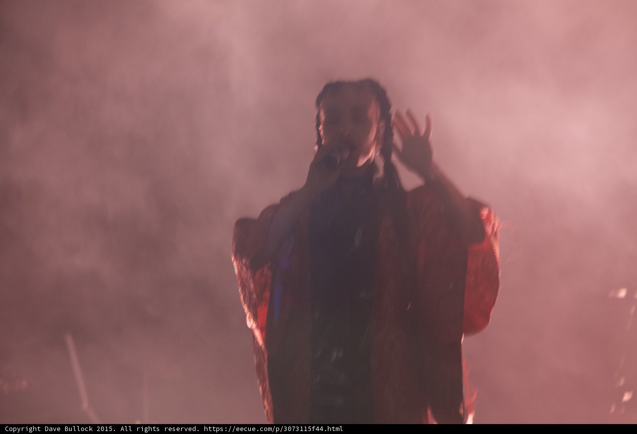 Travis Scott Performing Braids Pink Smoke Haze Microphone Hand Raised Patterned Jacket Motion Blur