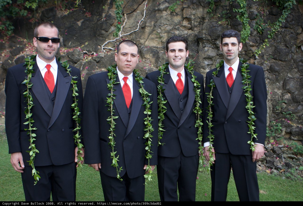 Four Men in Suits Pose Before Rock Wall