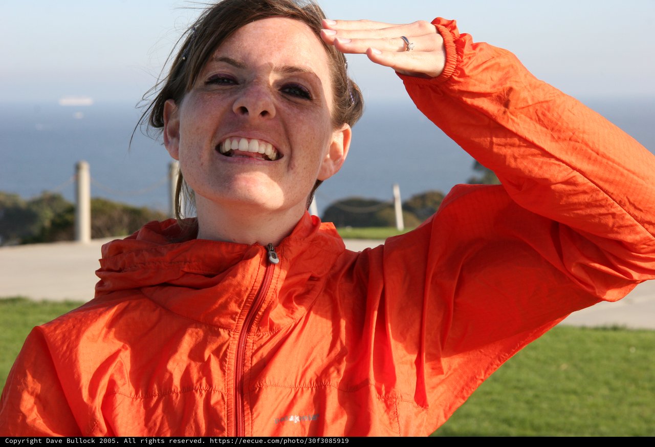 Smiling Woman Shielding Eyes in Orange Jacket