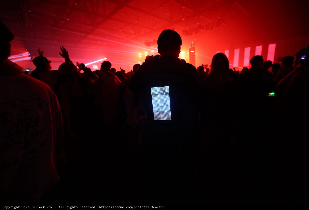 LED Backpack Glows Amid Red-Lit Festival Crowd