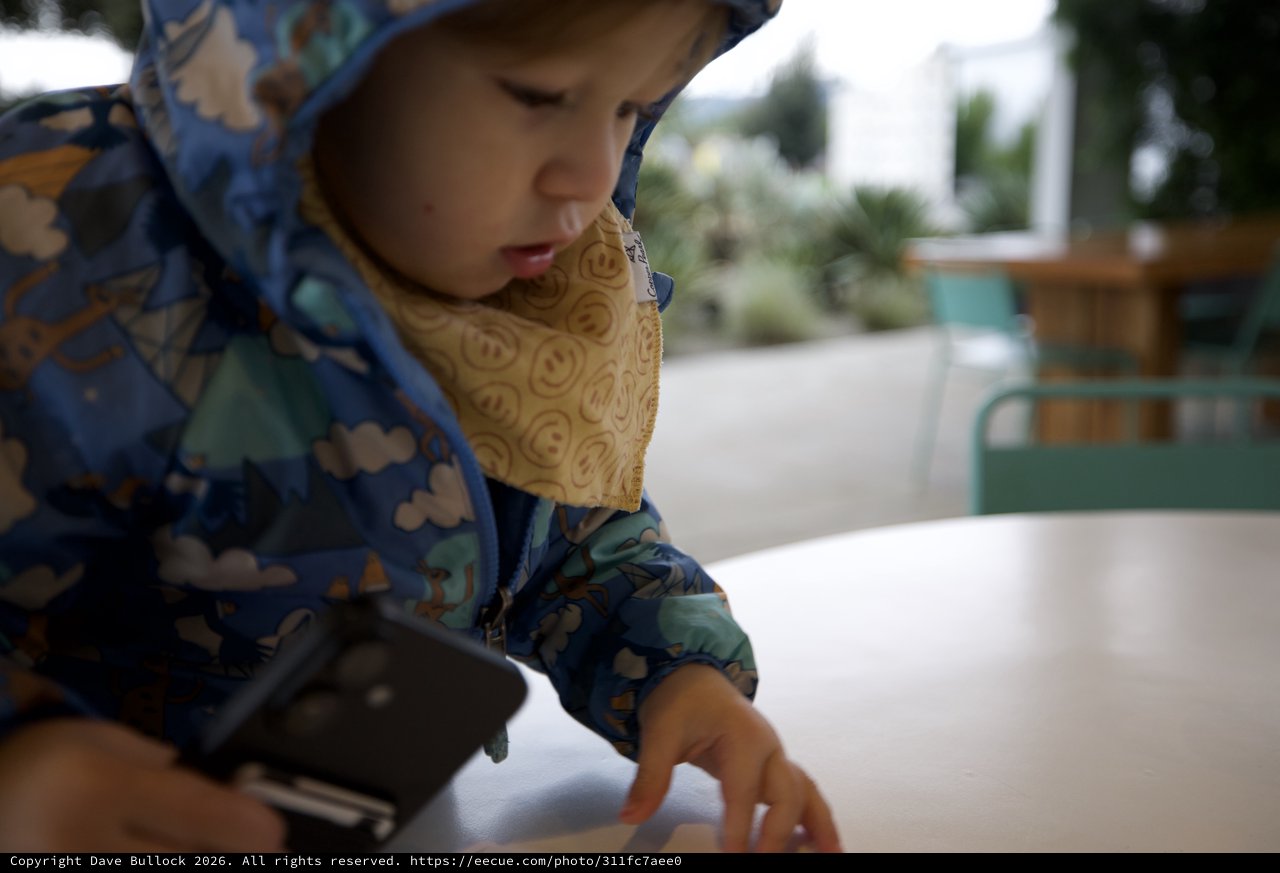 Young Child Examining Food at Outdoor Restaurant