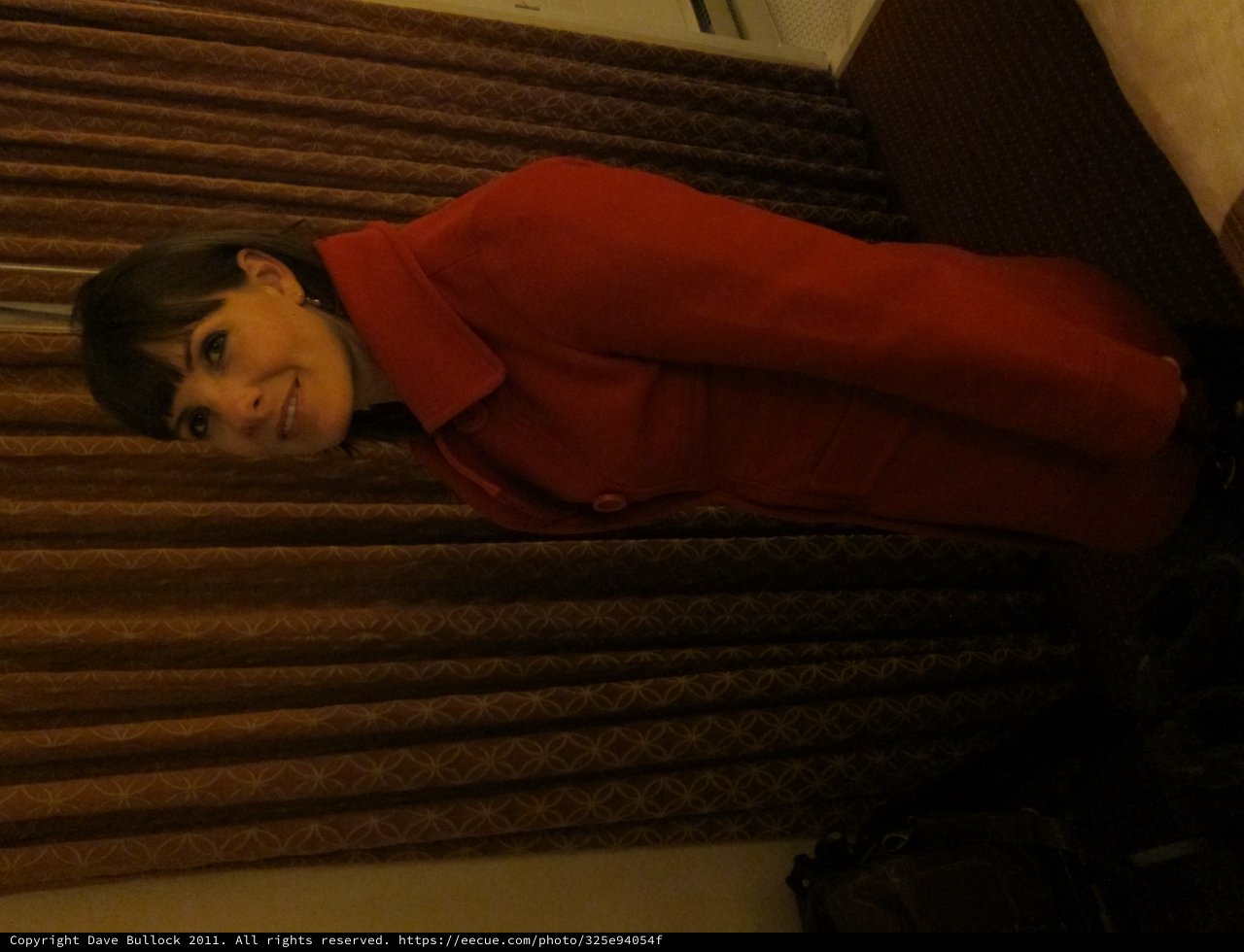 Woman in Red Coat Poses in Hotel Room
