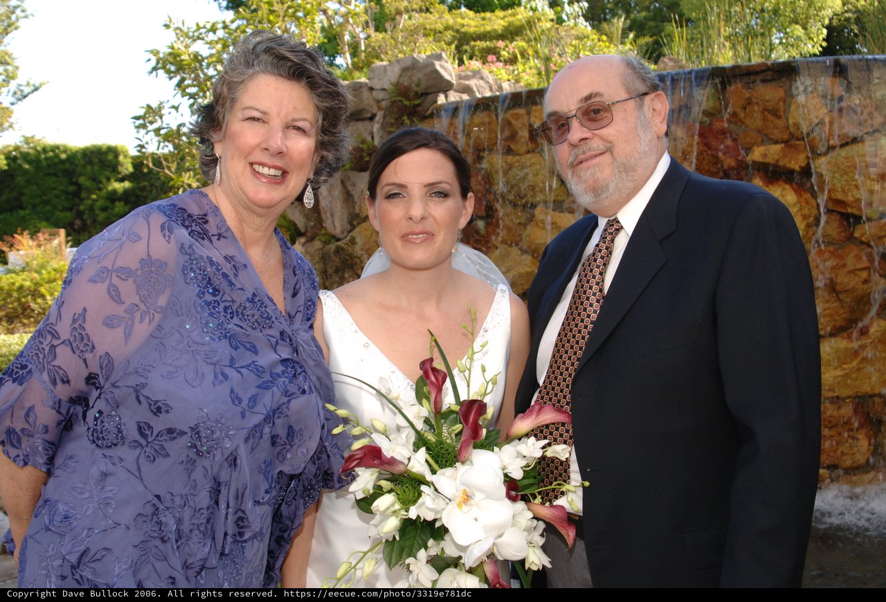 Bride Poses with Parents at Outdoor Wedding Ceremony