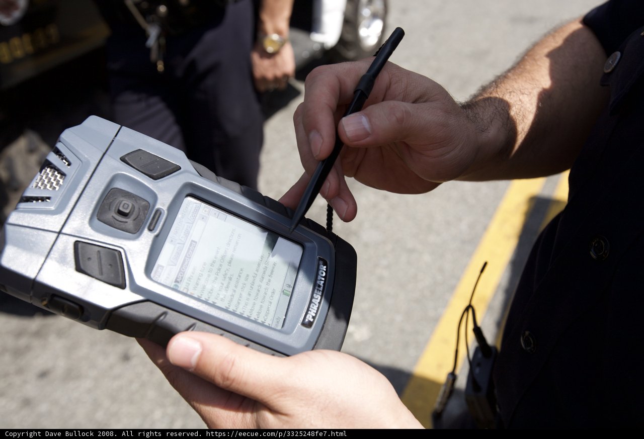 Police Officer Texting on Mobile Phone during Mayday Rally