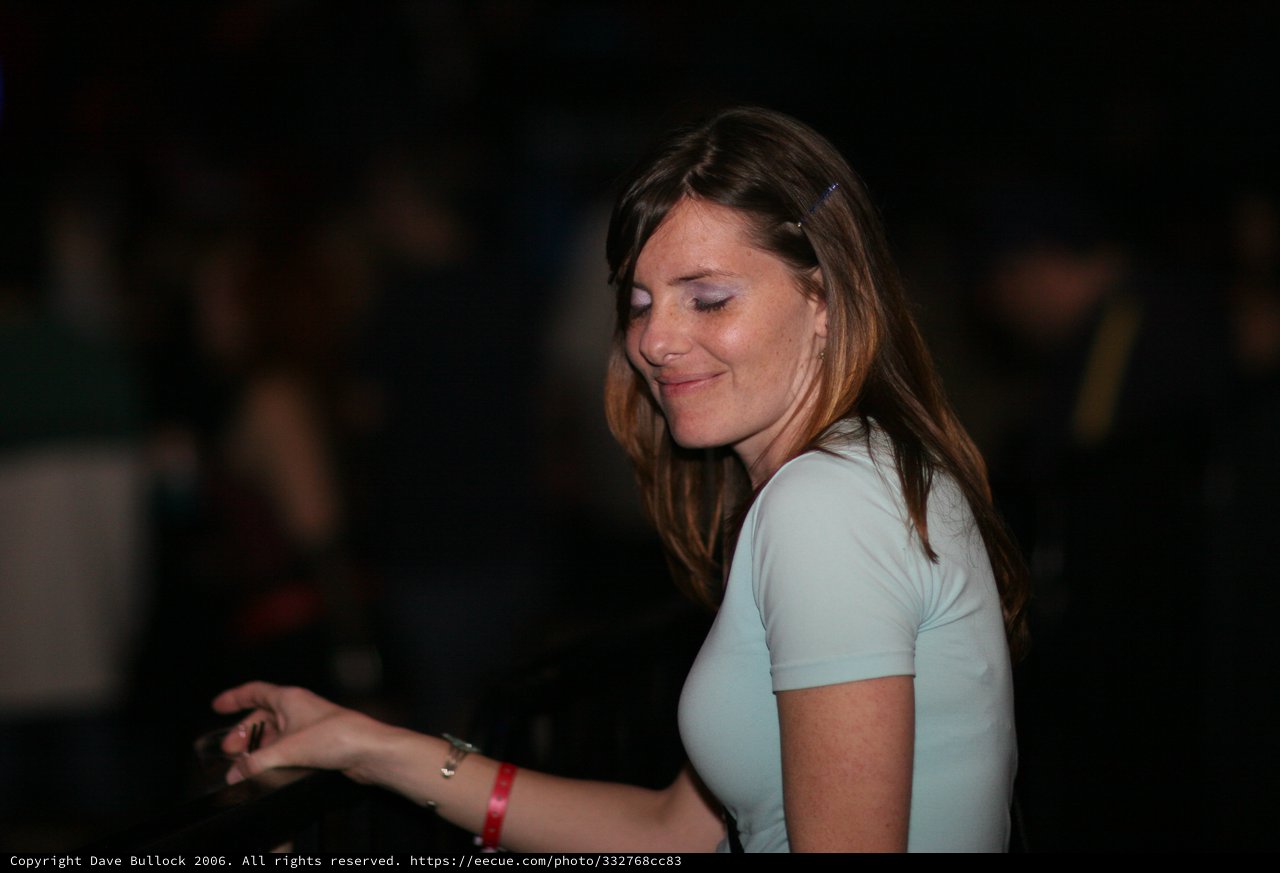Woman Smiling Softly at Dimly Lit Nighttime Event