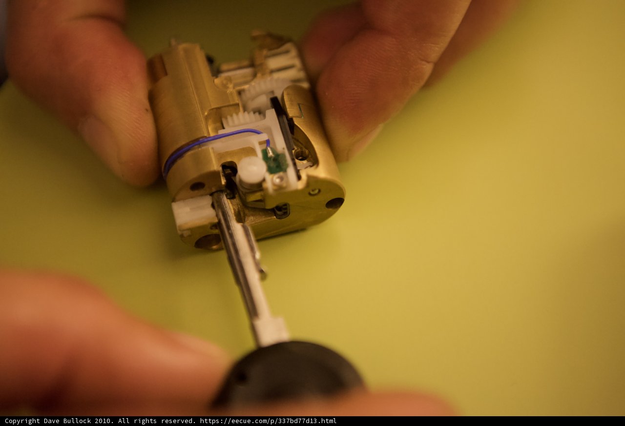 Electronic Device in Hand Caption: A person at Defcon 18 uses a small electronic device in their hand amidst a background of guns and weaponry.