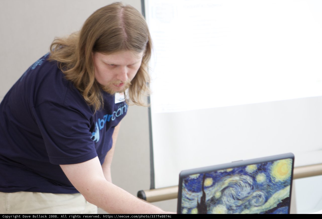 Blue-shirted man working on laptop