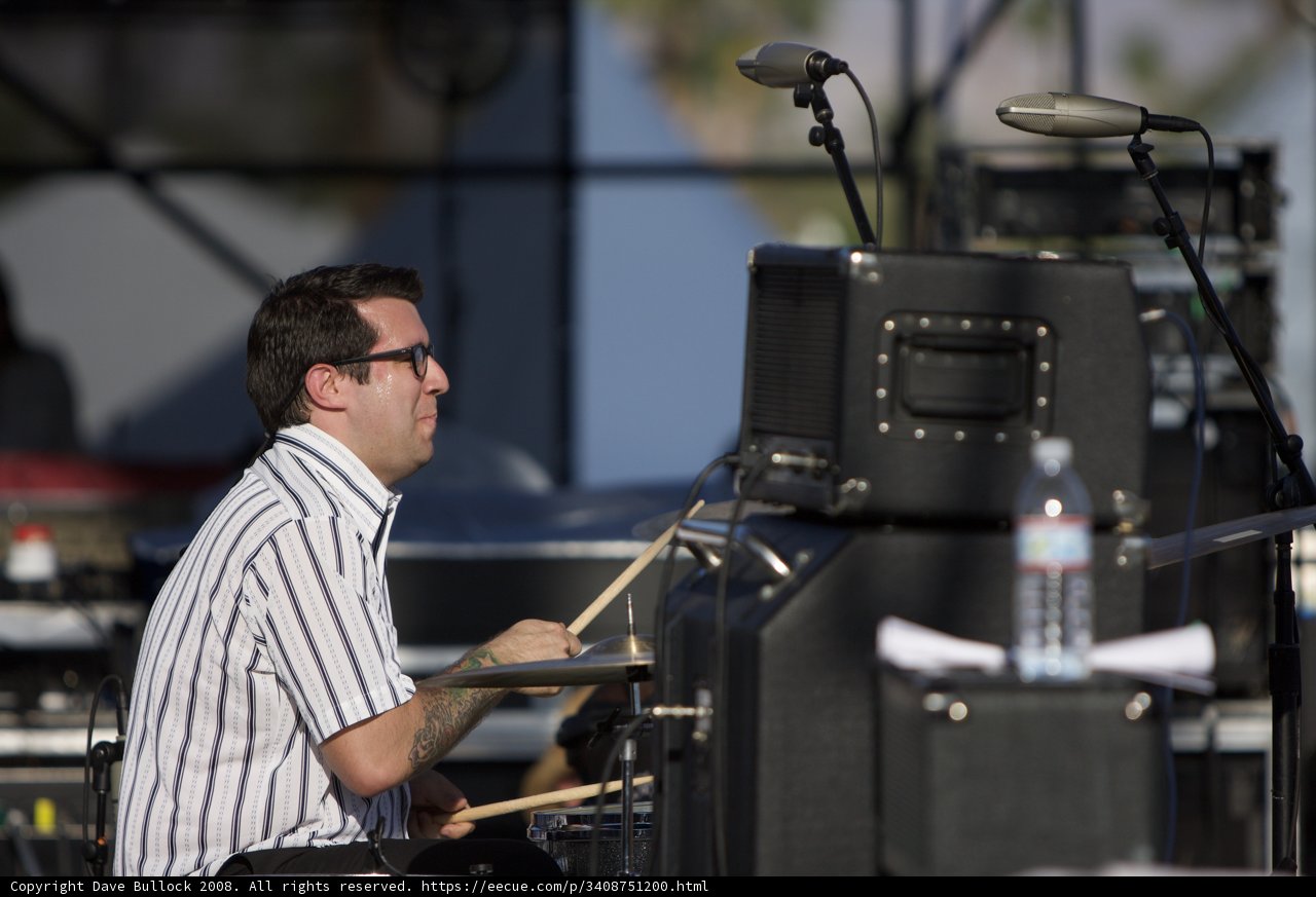 Showcase of Rhythm: Man in Striped Shirt Performing on Drums