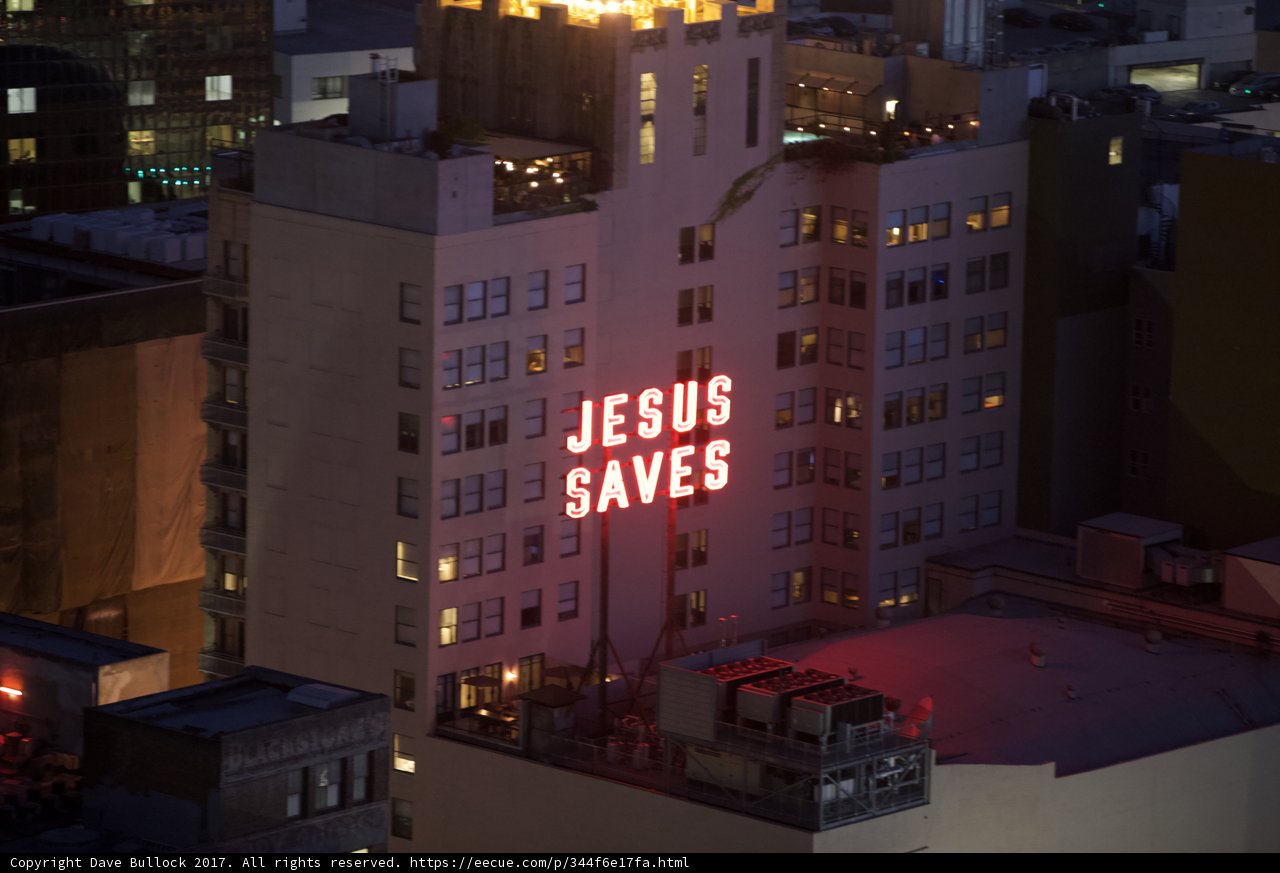 City Building with "Jesus Saves" Sign at Night