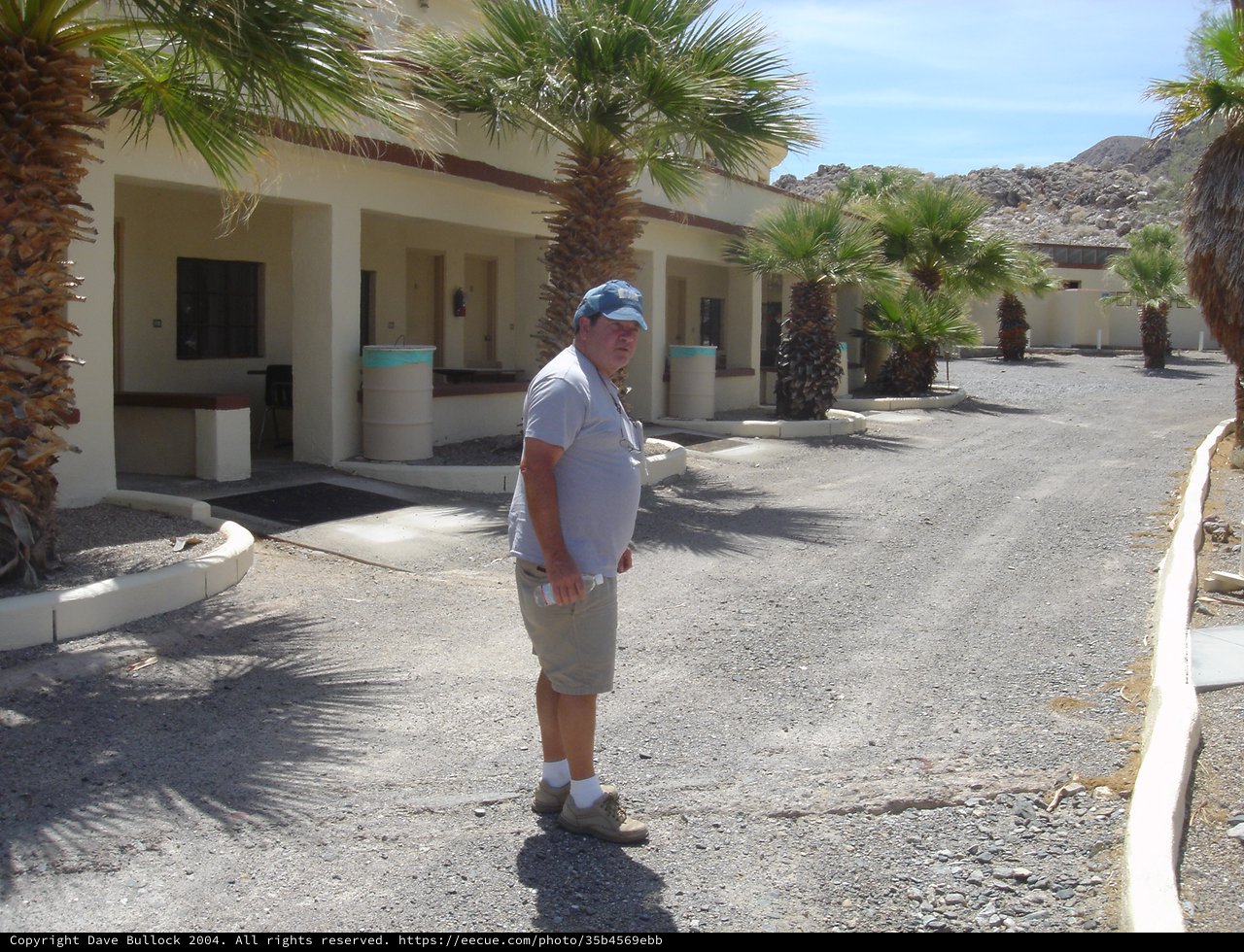 Man Stands at Abandoned Desert Motel Courtyard