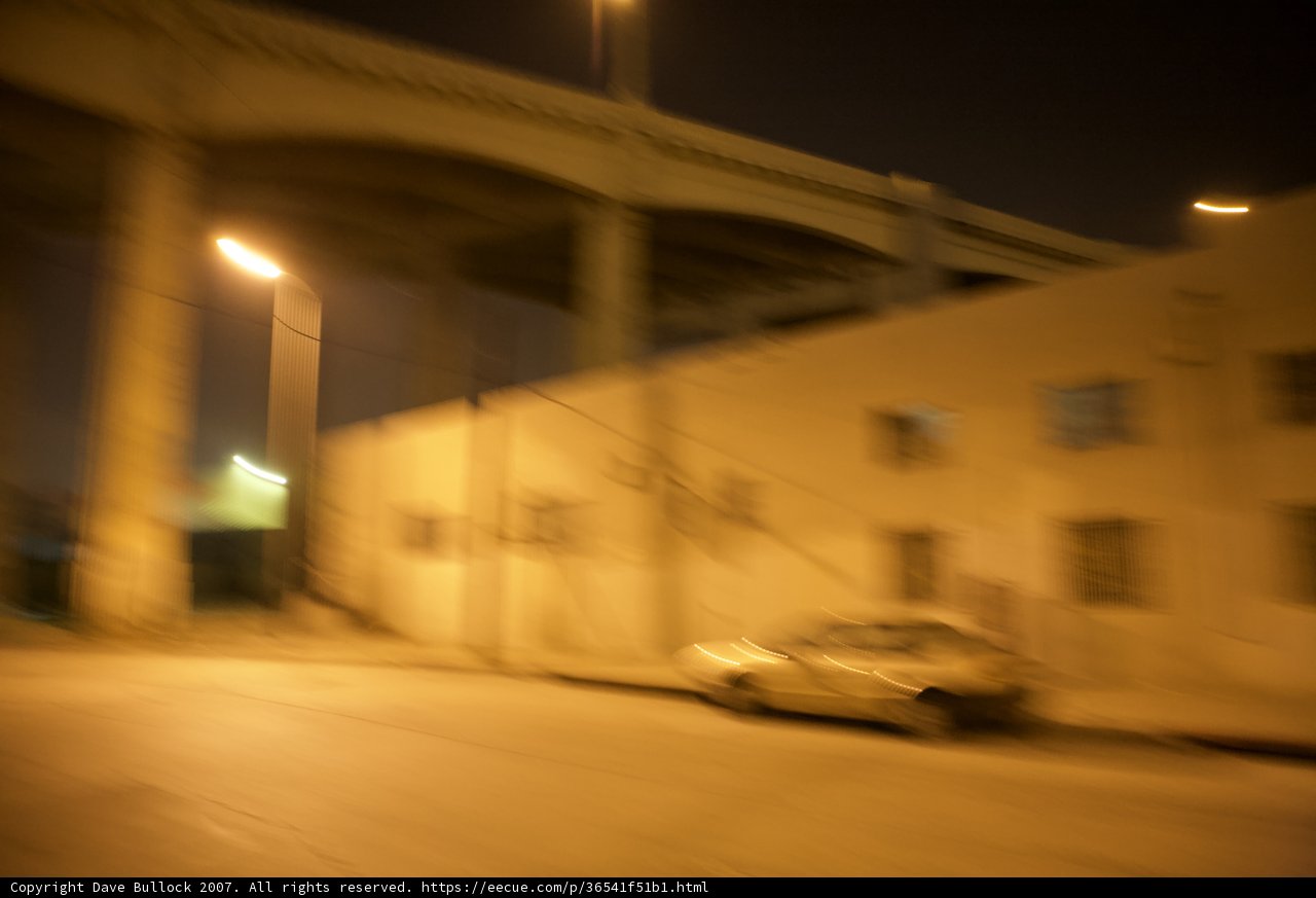 Blurred car travels down dimly lit road
