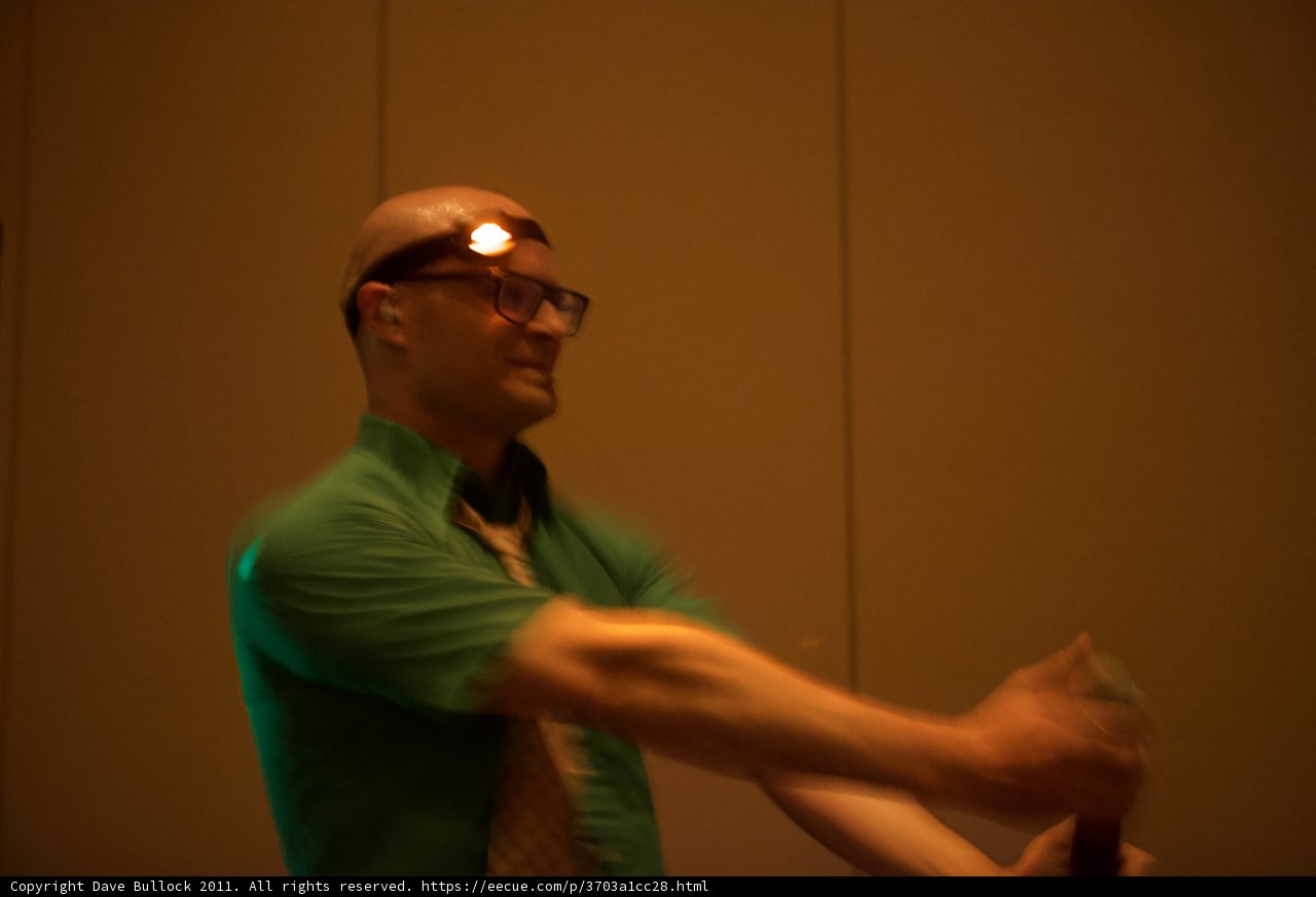 Green-Shirted Man Inspects Optical Equipment